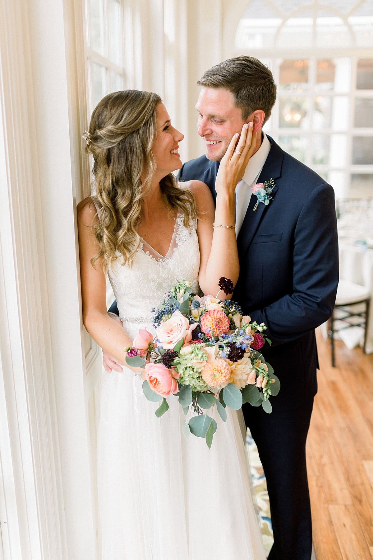 Arielle Peters Photography | Bride and groom smiling by big windows at Sycamore Hills Golf Club in Fort Wayne, Indiana on wedding day.