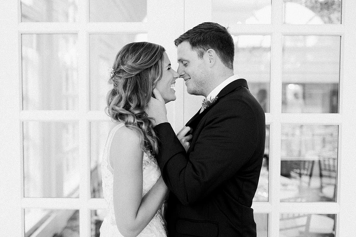 Arielle Peters Photography | Bride and groom kissing by big windows at Sycamore Hills Golf Club in Fort Wayne, Indiana on wedding day.