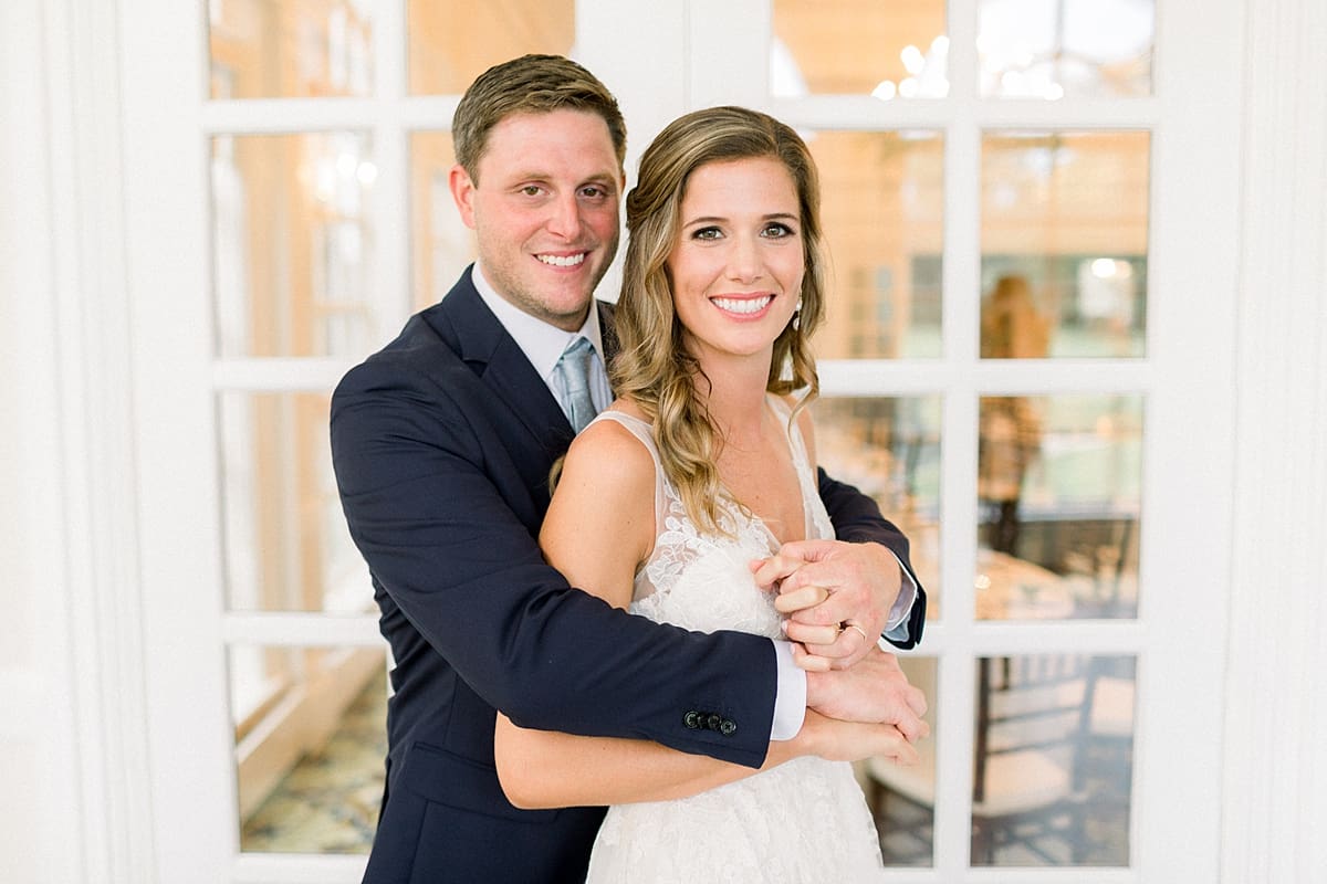 Arielle Peters Photography | Bride and groom smiling by big windows at Sycamore Hills Golf Club in Fort Wayne, Indiana on wedding day.