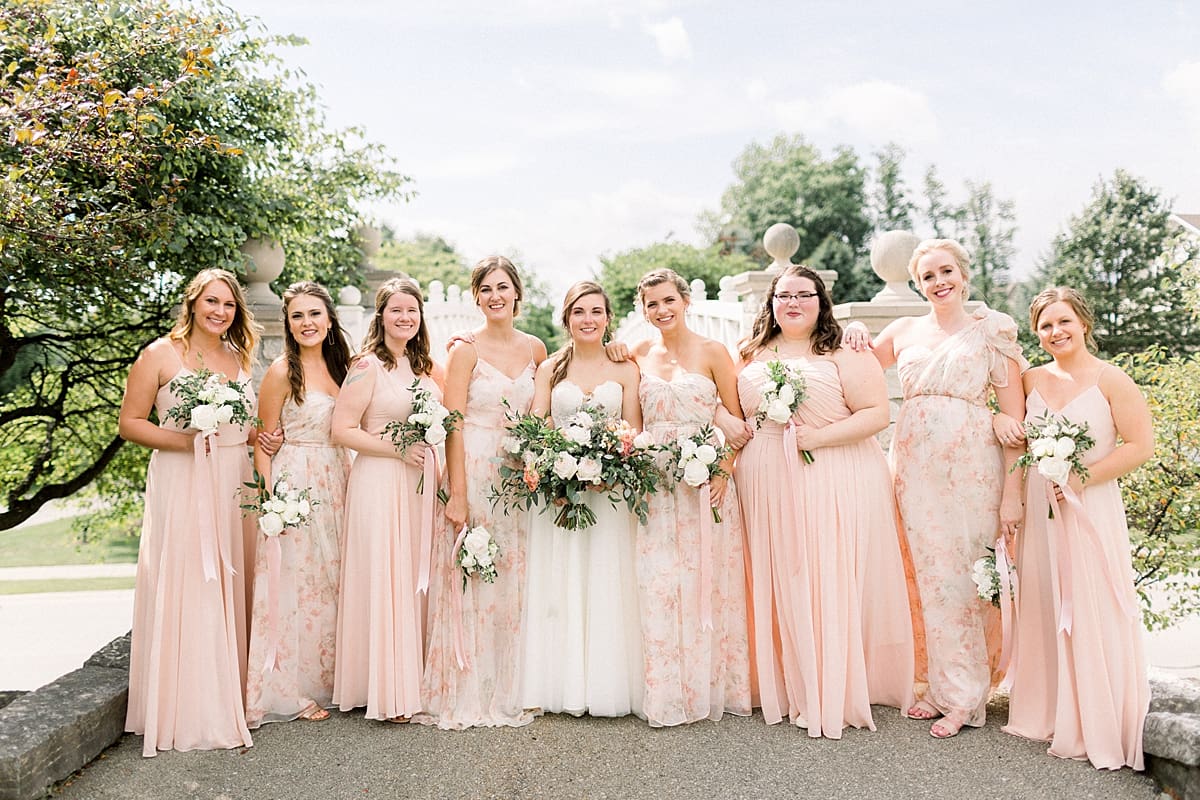 Arielle Peters Photography | Bride and bridesmaids smiling outside with bouquets at The Bridgewater Club in Carmel, Indiana on wedding day.