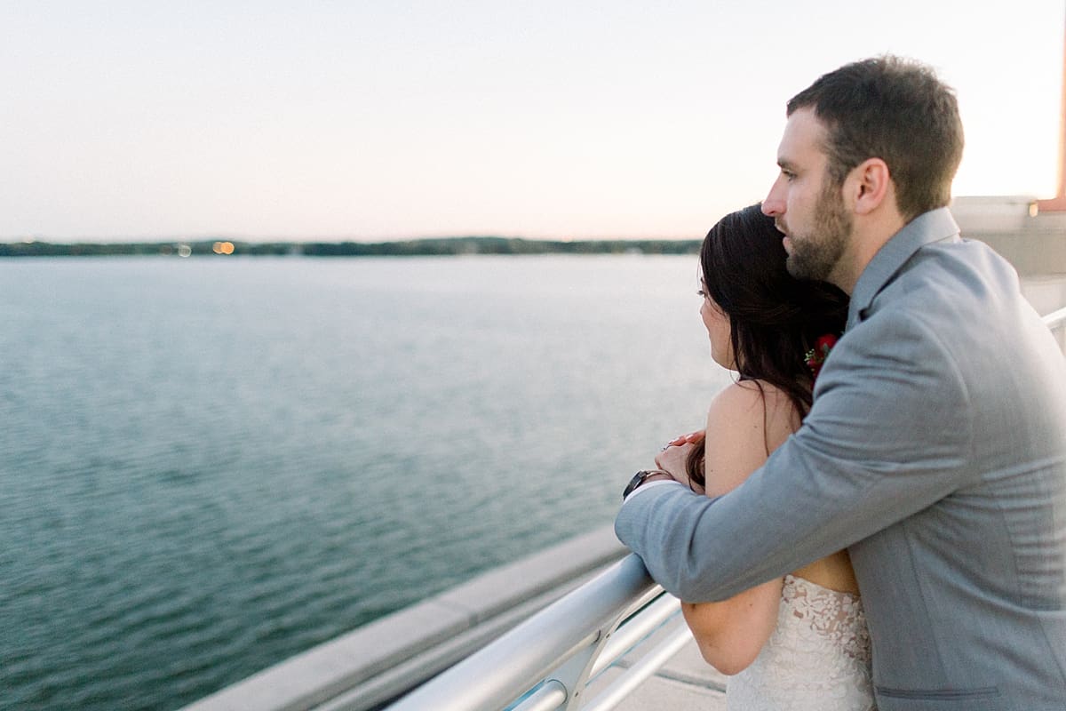 Arielle Peters Photography | Groom holding bride in her arms by the water in Madison, Wisconsin on wedding day.