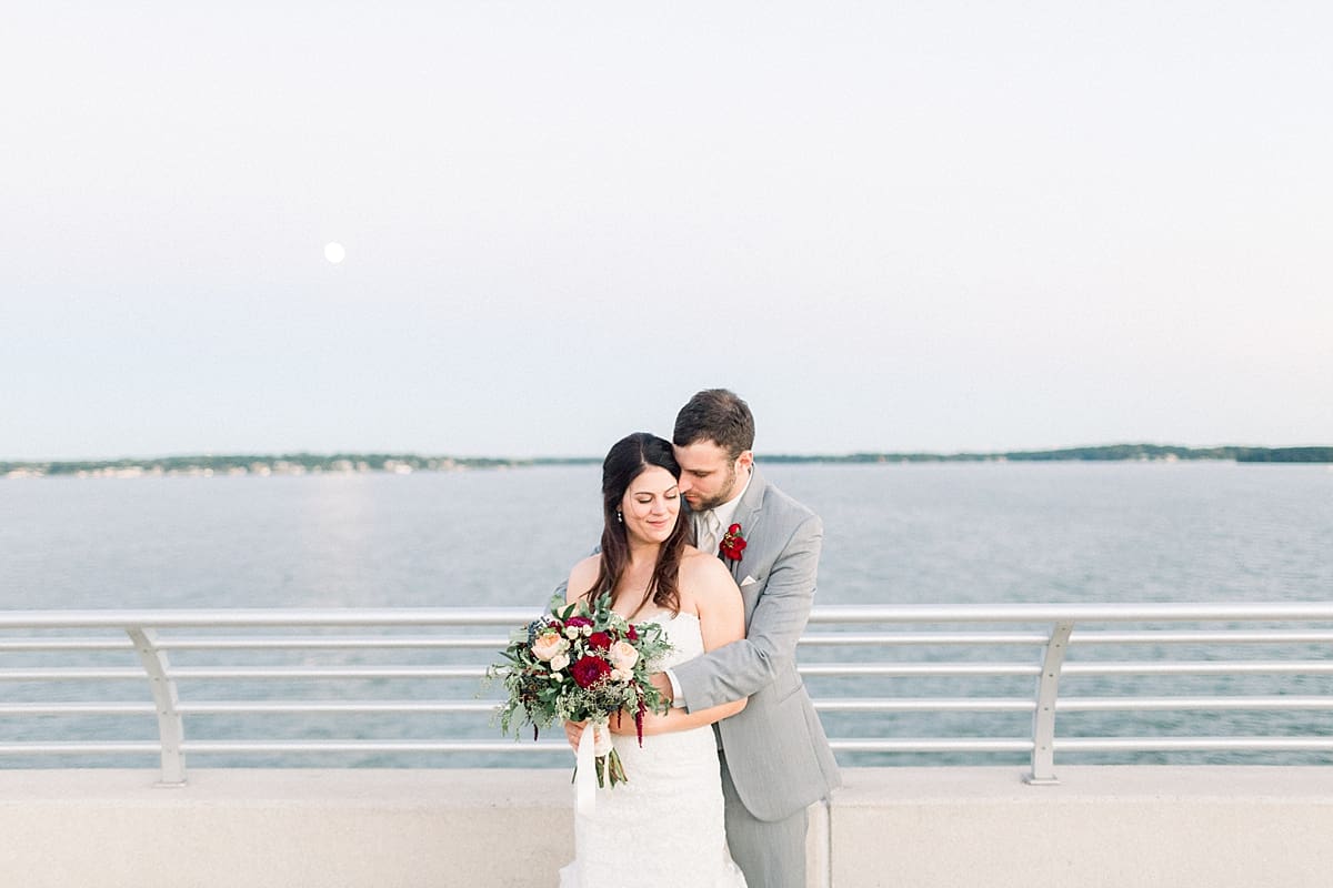 Arielle Peters Photography | Groom holding bride in her arms by the water in Madison, Wisconsin on wedding day.
