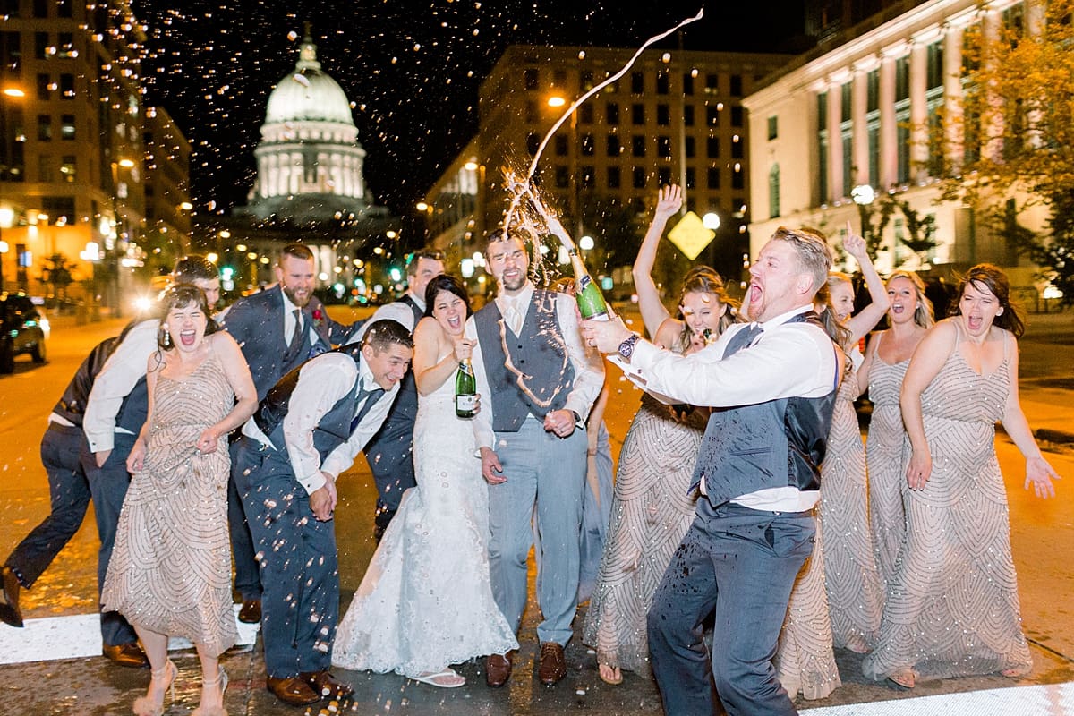 Arielle Peters Photography | Bride and groom and wedding party spraying champagne on streets in Madison, Wisconsin on wedding day.