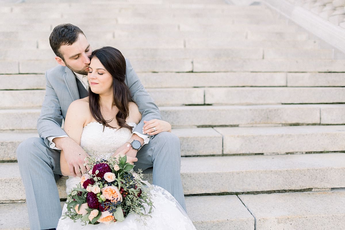 Arielle Peters Photography |  Groom kissing the bride sitting on stairs outside Monona Terrace in Madison, Wisconsin on wedding day.