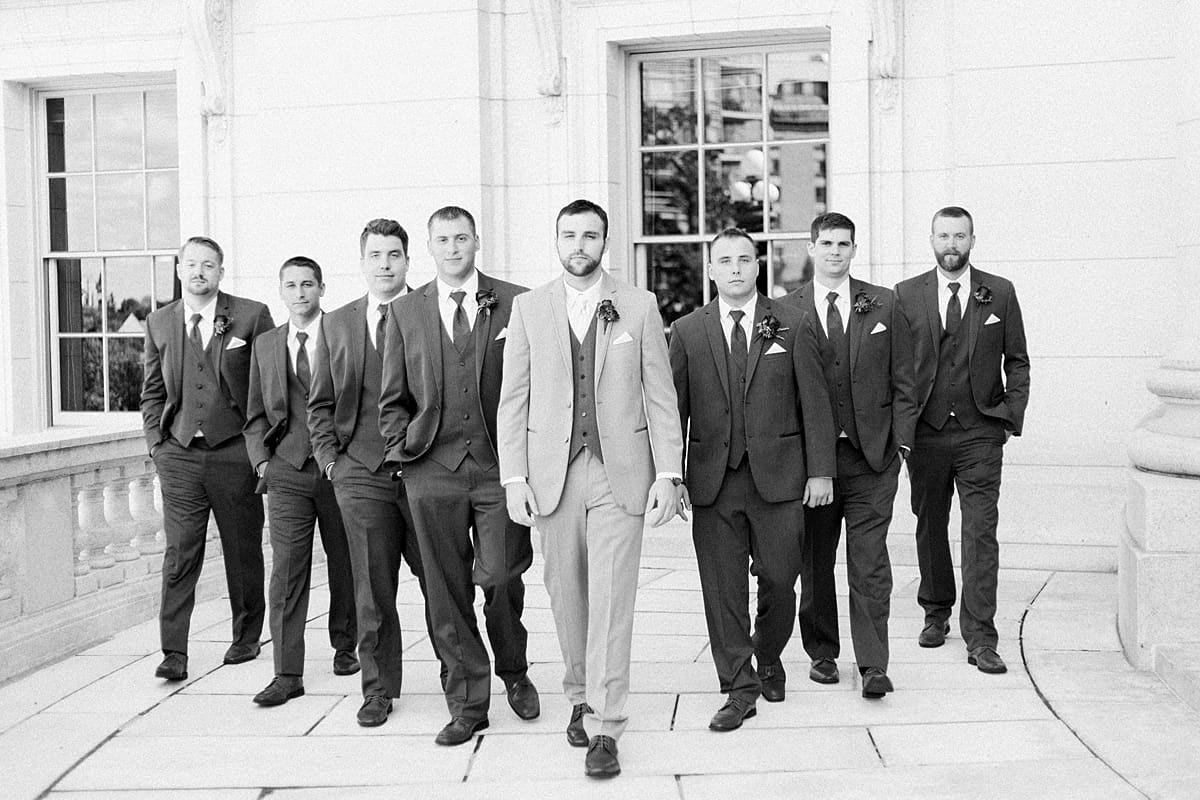 Arielle Peters Photography | Groom and groomsmen walking with serious faces outside Monona Terrace in Madison, Wisconsin on wedding day.
