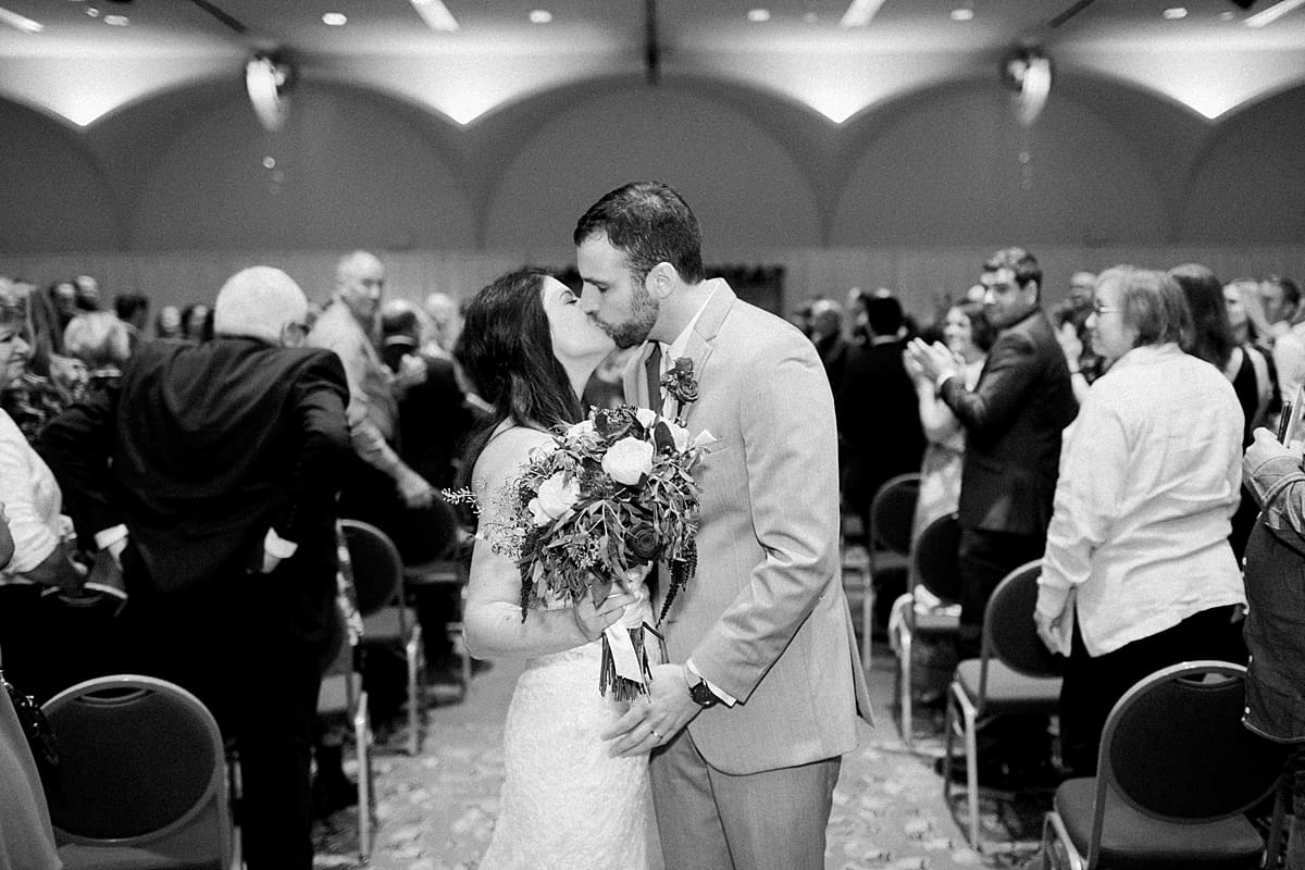 Arielle Peters Photography | Bride and groom kissing at end of aisle on wedding day in Monona Terrace in Madison, Wisconsin. 