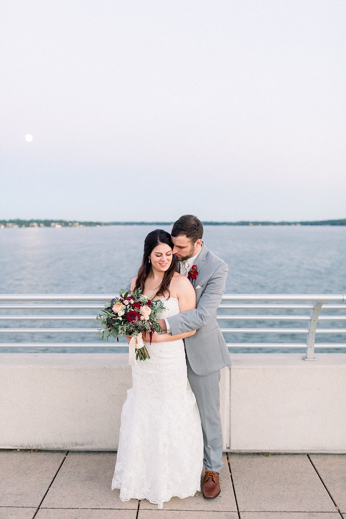 Arielle Peters Photography | Groom holding bride in her arms by the water in Madison, Wisconsin on wedding day.