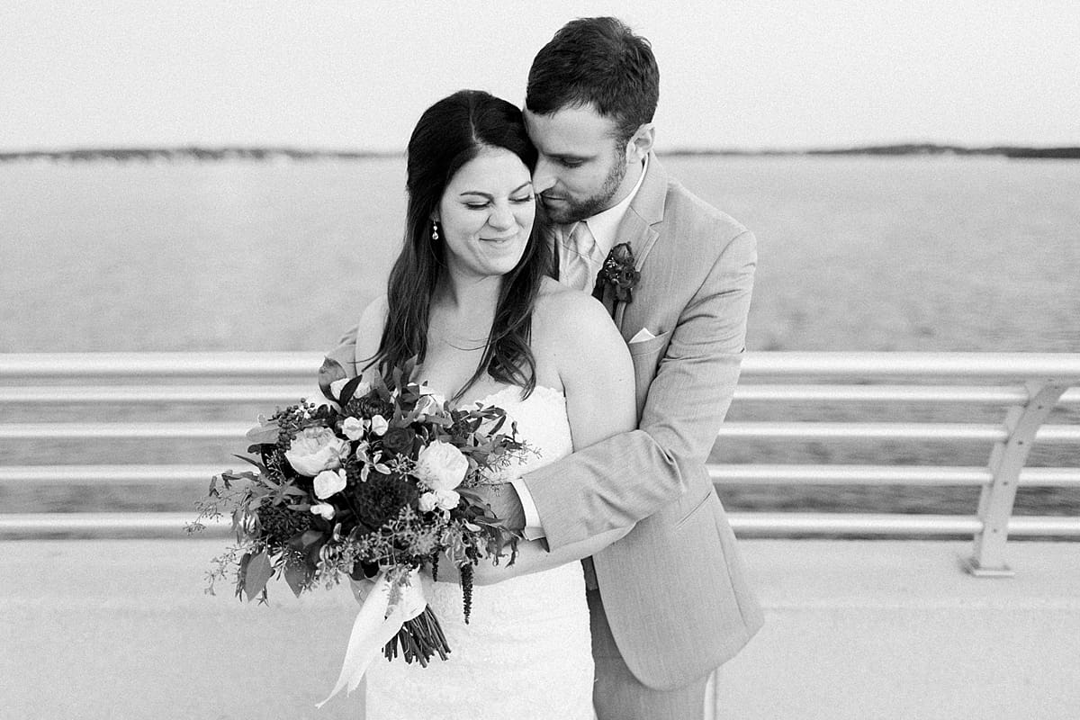 Arielle Peters Photography | Groom holding bride in her arms by the water in Madison, Wisconsin on wedding day.