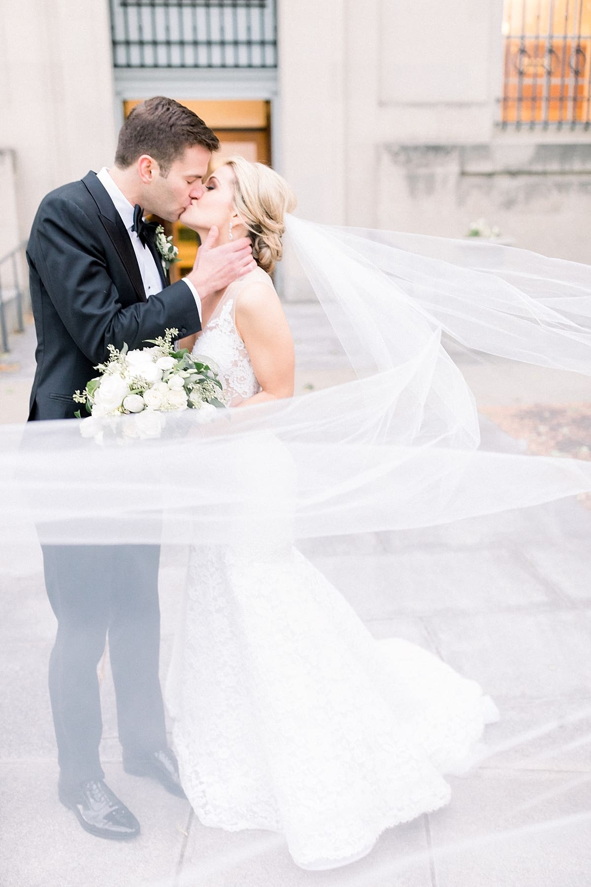 Arielle Peters Photography | Bride and groom kissing with veil flowing in the wind in Indianapolis on wedding day.