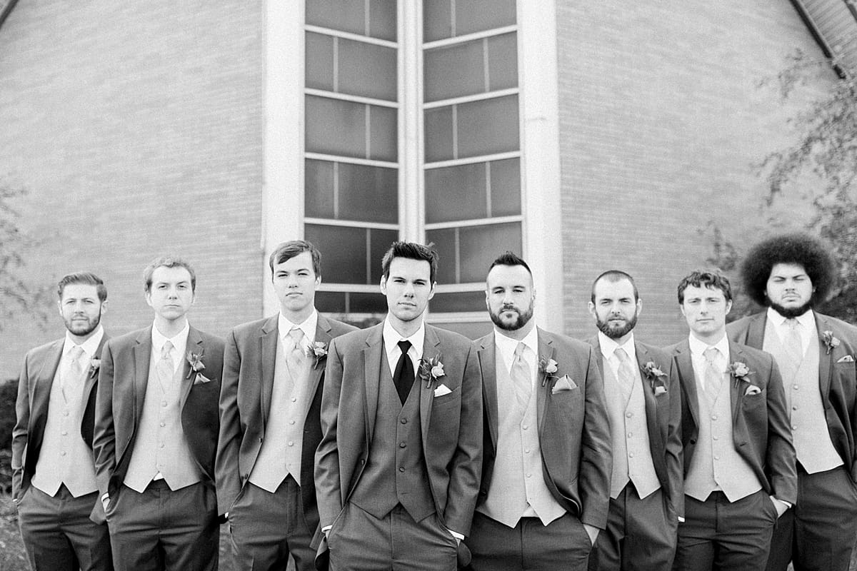 Arielle Peters Photography | Groom and groomsmen lined up with serious faces outside on fall wedding day.