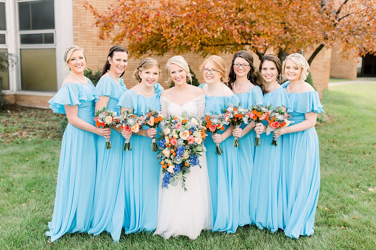Arielle Peters Photography | Bride and bridesmaids lined up with bouquets smiling outside on fall wedding day.