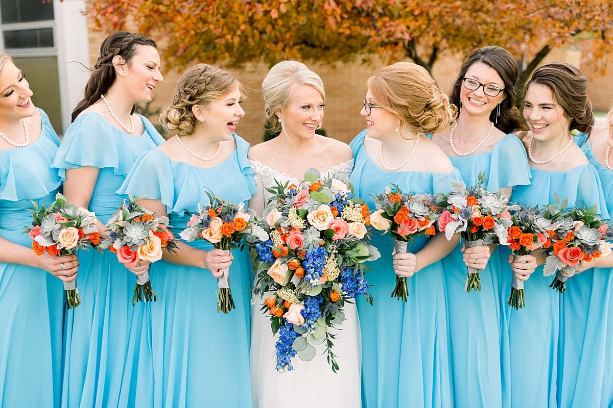 Arielle Peters Photography | Bride and bridesmaids lined up with bouquets laughing outside on fall wedding day.