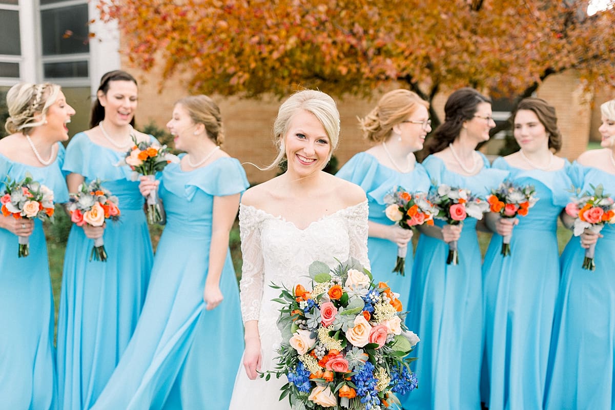 Arielle Peters Photography | Bride and bridesmaids smiling with bouquets outside on fall wedding day.
