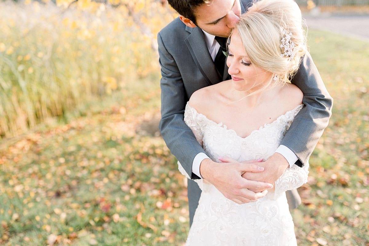 Arielle Peters Photography | Groom kissing the bride's forehead outside in a field on fall wedding day.