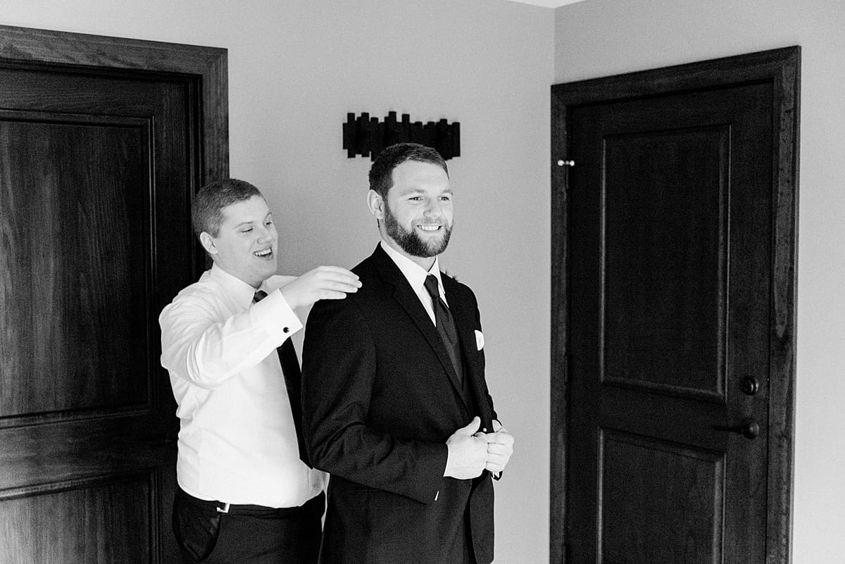 Arielle Peters Photography | Groom getting dressed on wedding day with groomsman.