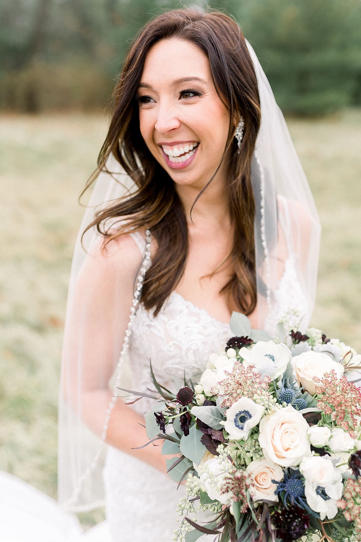 Arielle Peters Photography | Bride in wedding dress with flowers in field on wedding day.