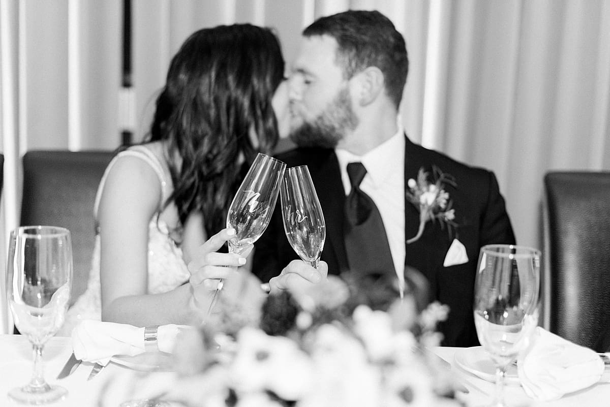 Arielle Peters Photography | Bride and groom kissing and clinking classes at wedding reception.