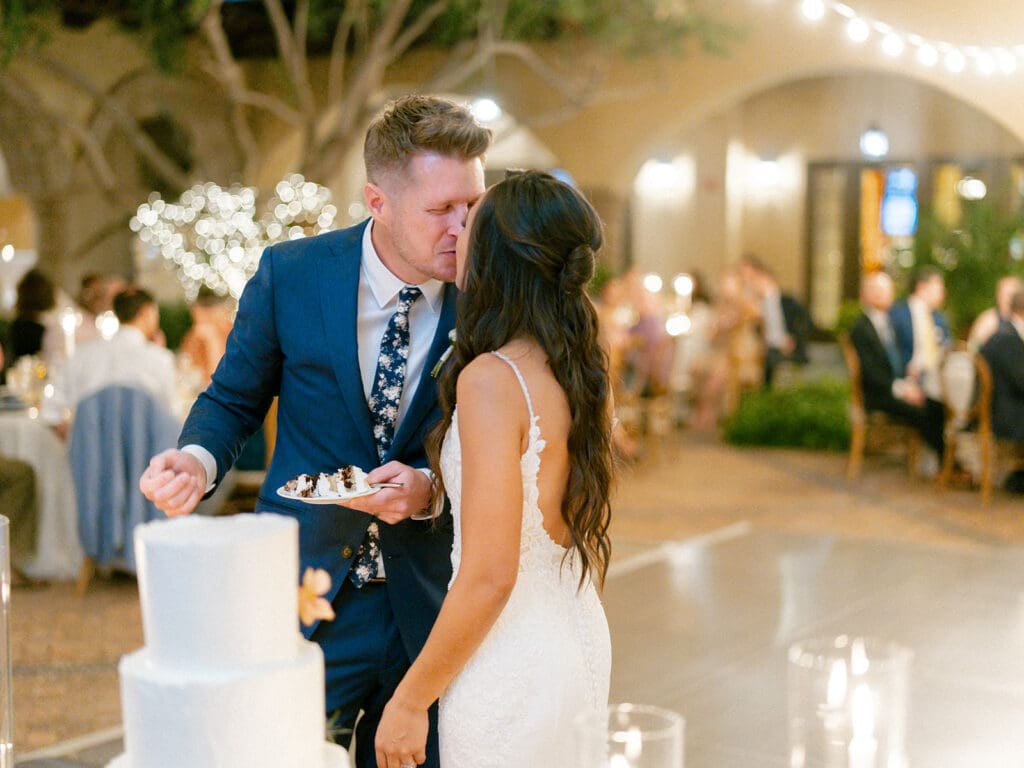 Bride and groom kissing after cutting their wedding cake