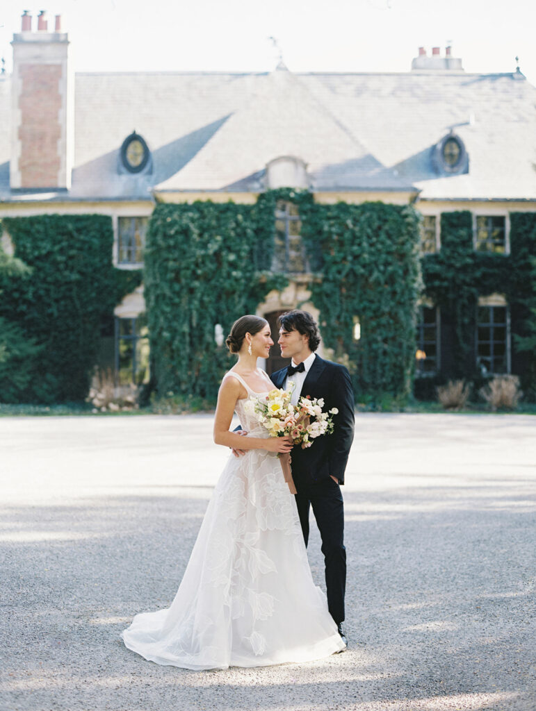 Bride and groom smiling at each other in front of Greencrest Manor in Battle Creek, Michigan