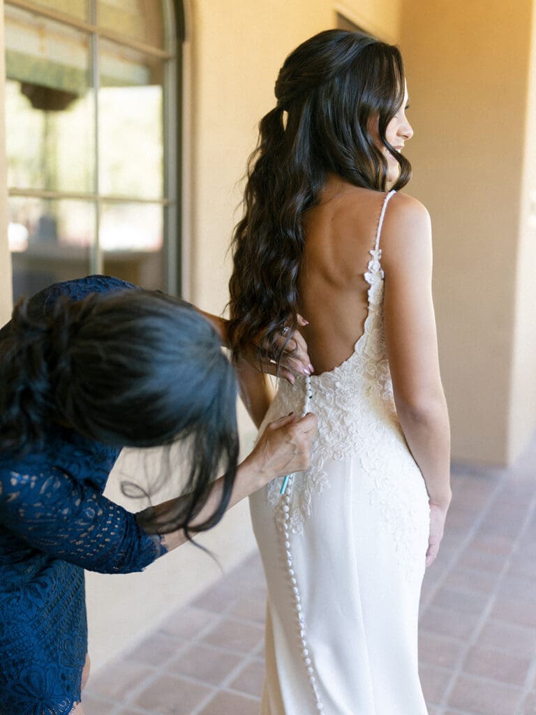 Brides mother buttoning her wedding dress up