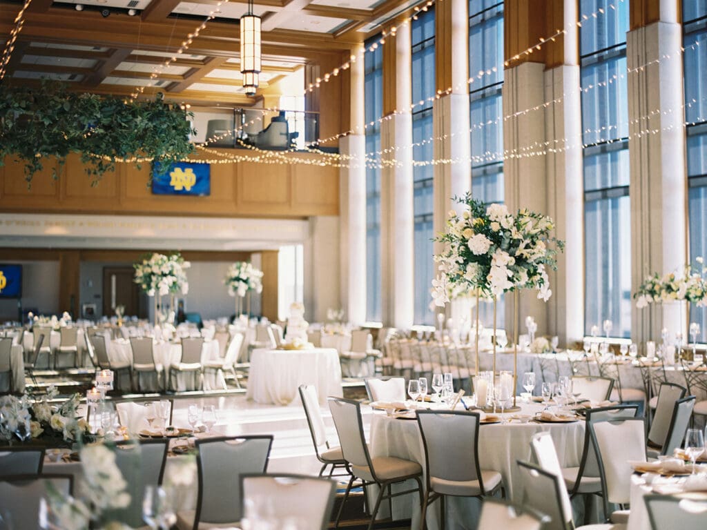An indoor Notre Dame wedding reception in Dahnke Ballroom with gold and white accents and white florals