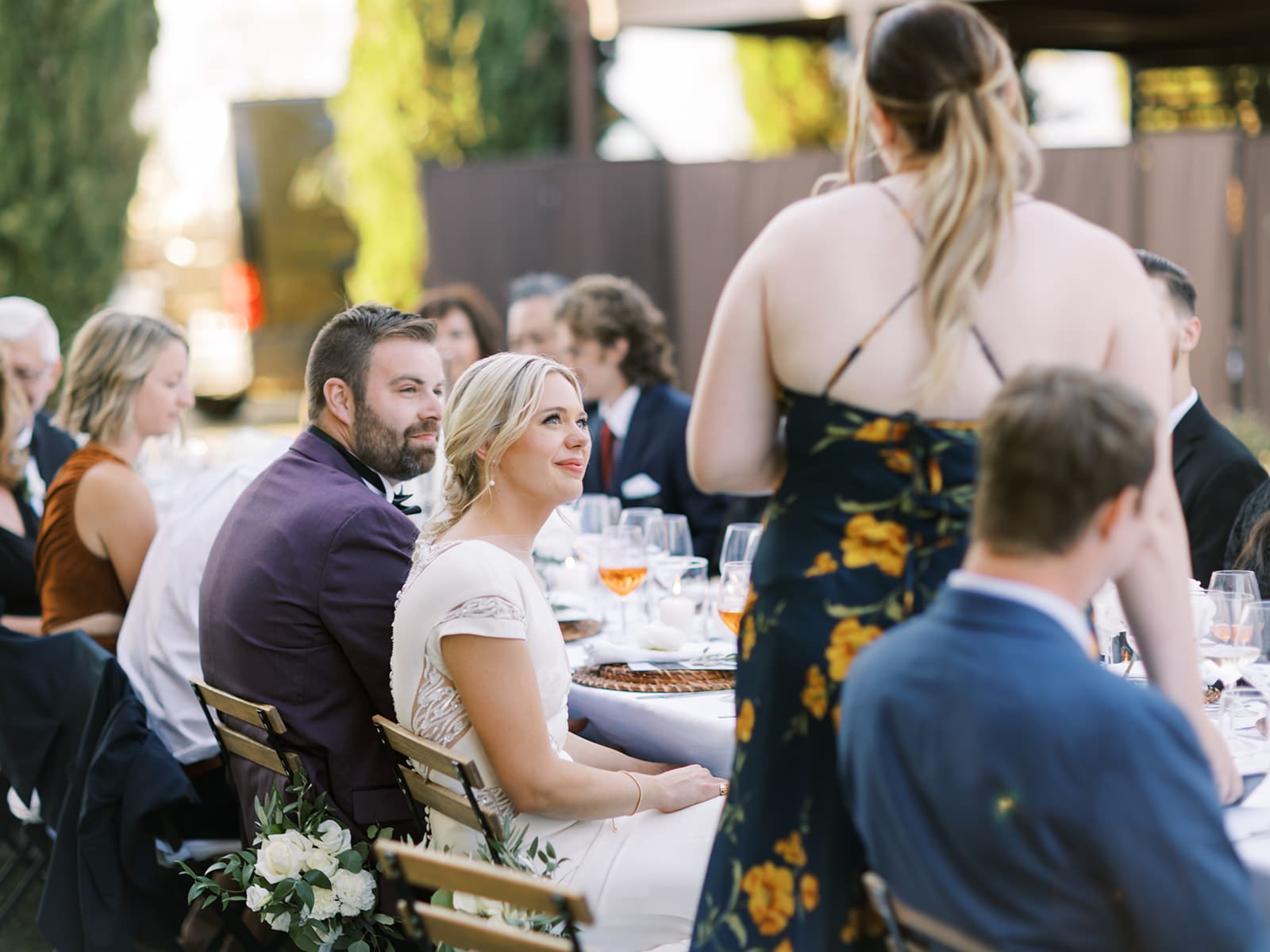 Bride and groom listening to speeches at their outdoor summer wedding reception