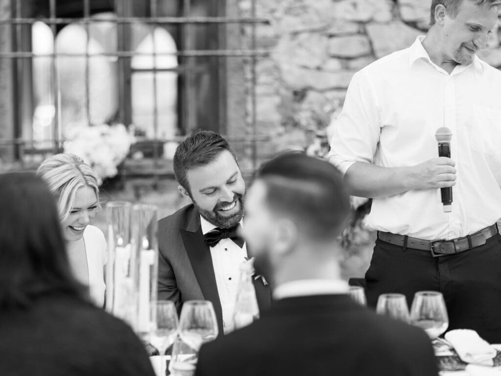 Black and white photo of a bride and groom laughing during wedding speeches