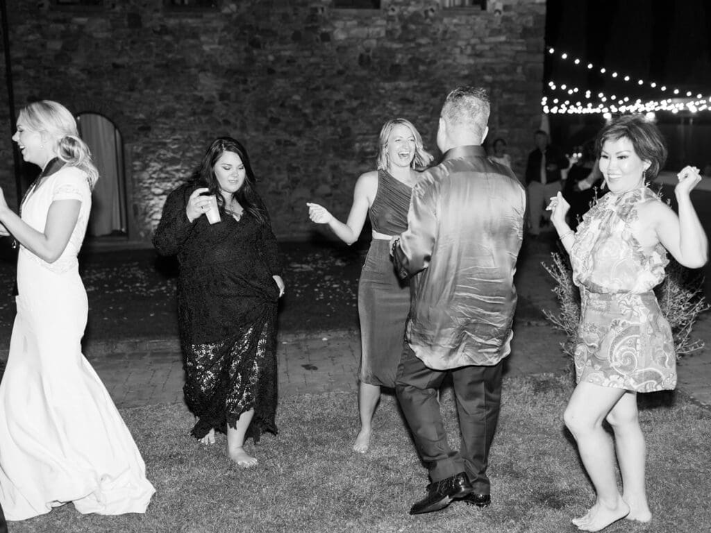 Black and white photo of wedding guests dancing during the reception