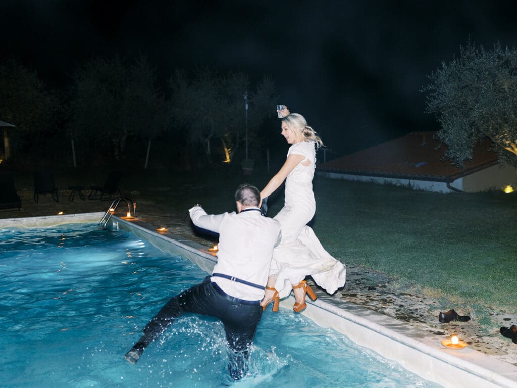 Bride and groom jumping into a pool together during their reception