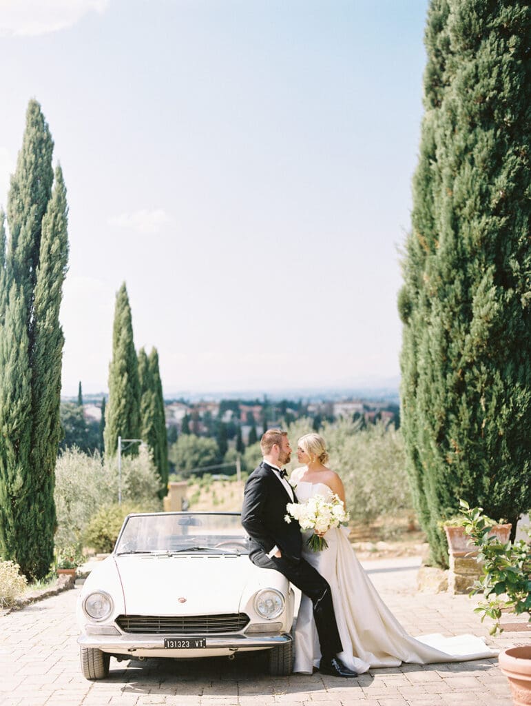 Bride and grooms portraits with a classic white car from their summer wedding in Tuscany, Italy at Villa Petrea