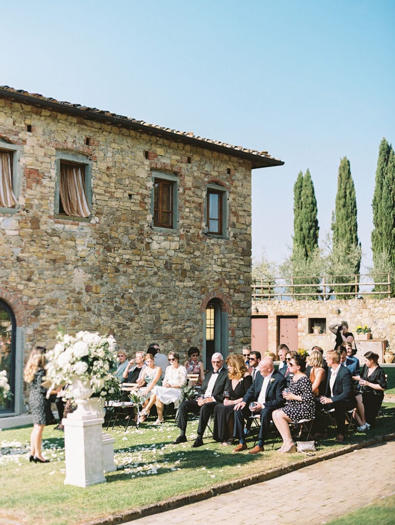 Guests sitting for an outdoor summer wedding ceremony in the hills of Tuscany, Italy