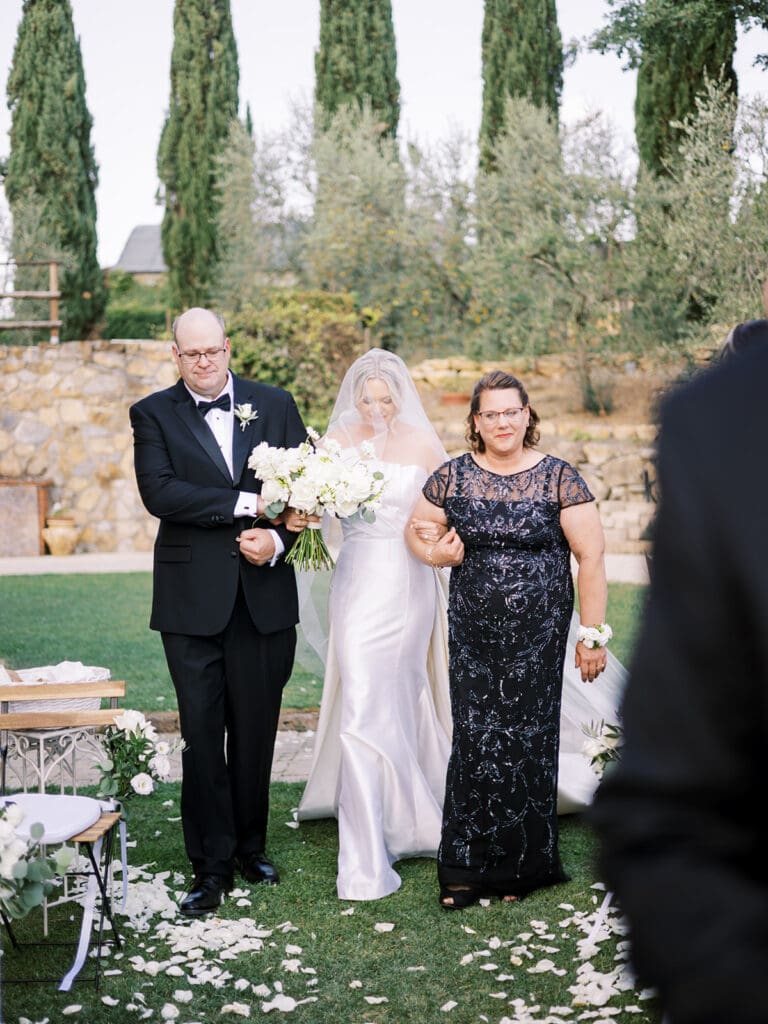 Bride being walked down the aisle by her parents. 