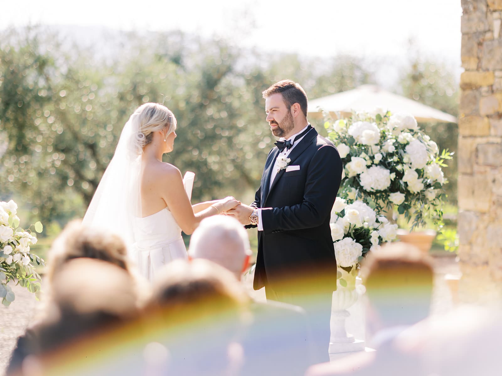 Bride and groom holding hands during their outdoor summer wedding ceremony at Villa Petrea in the hills of Tuscany, Italy.