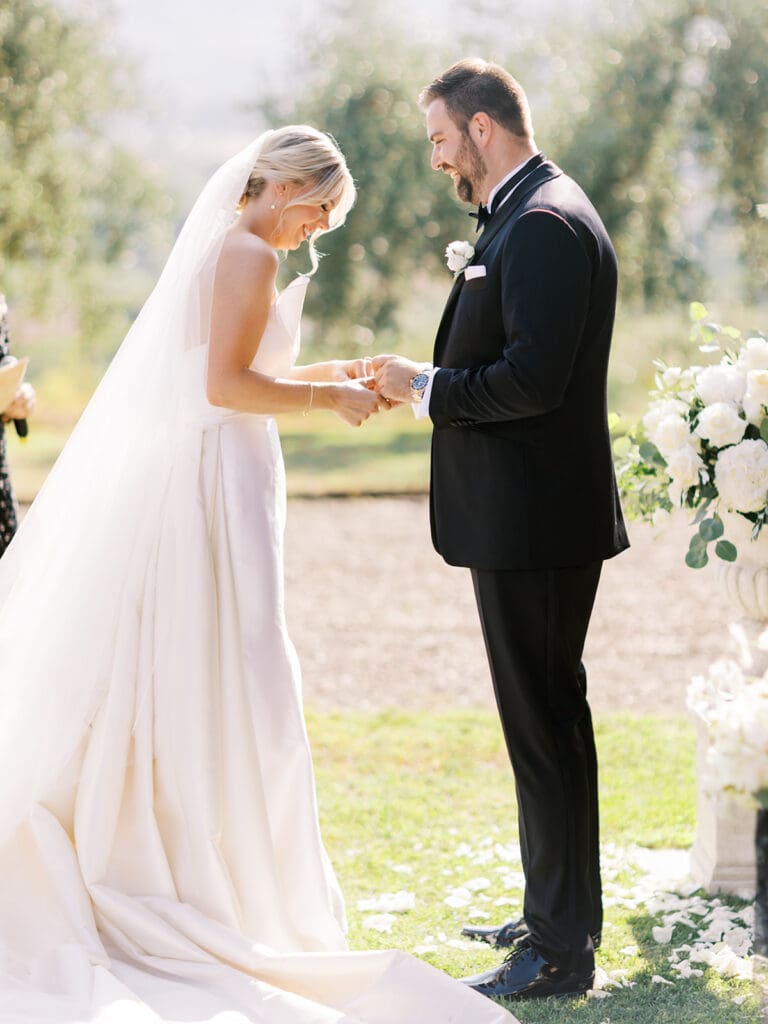 Bride and groom holding hands during their outdoor summer wedding ceremony at Villa Petrea in the hills of Tuscany, Italy.