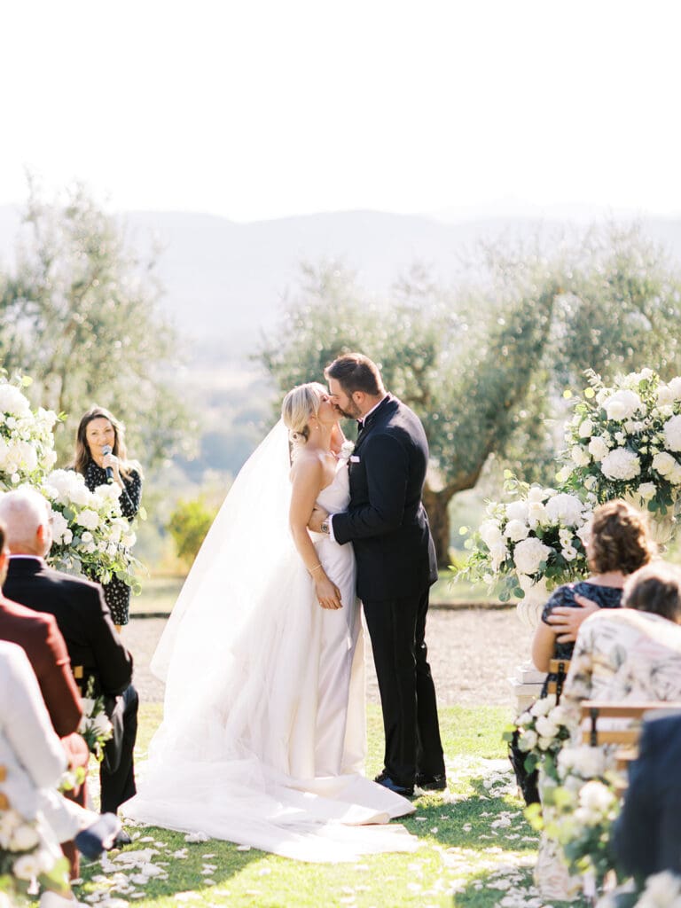 Bride and groom kissing during their outdoor summer wedding ceremony at Villa Petrea in the hills of Tuscany, Italy.