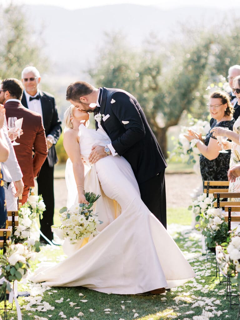 Bride and groom kissing after their outdoor summer wedding ceremony at Villa Petrea in the hills of Tuscany, Italy.
