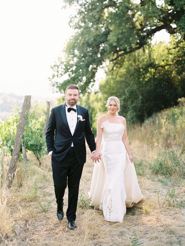 Bride and grooms outdoor summer wedding portraits walking in the hills of Tuscany, Italy.