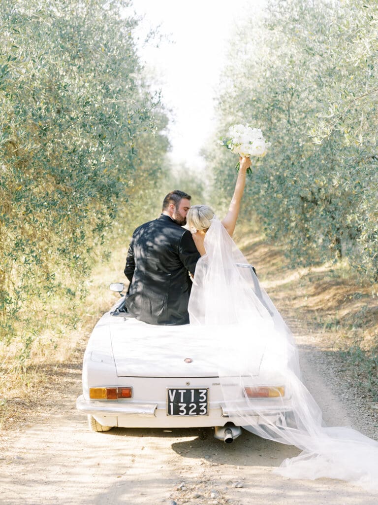 Couple sitting in a classic white car for their summer wedding in Tuscany, Italy at Villa Petrea