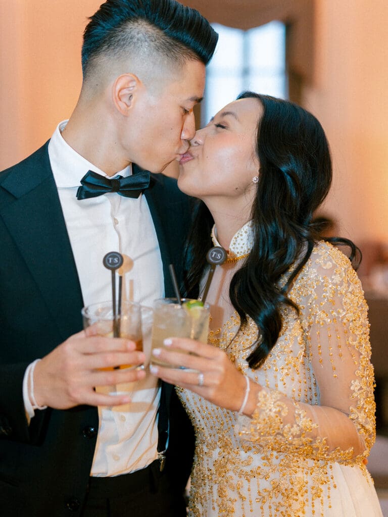 Bride and groom kissing with drinks in hands at their Indiana wedding reception