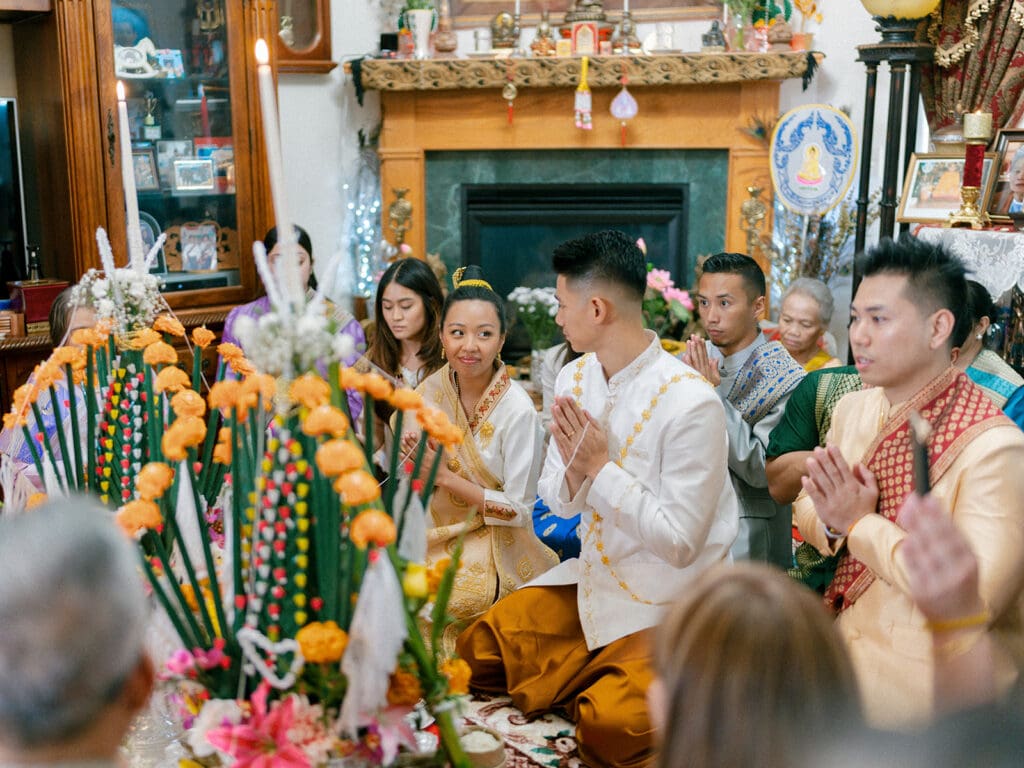 Bride and groom praying with their family during their at-home Lao and Vietnamese wedding ceremony