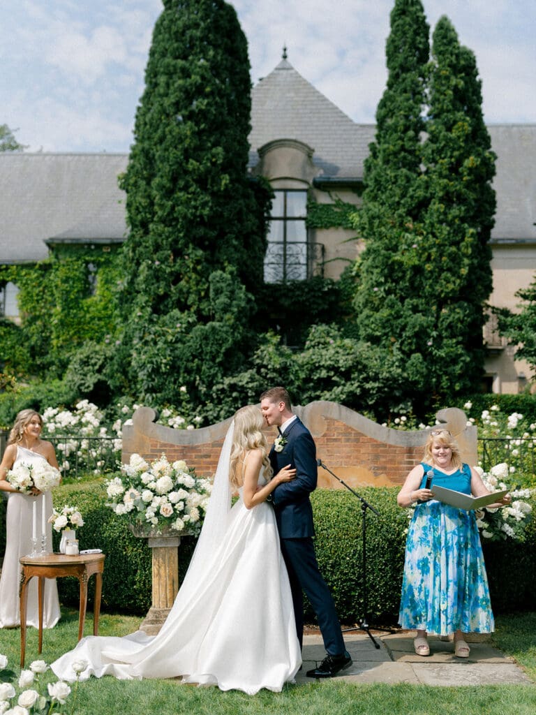 Bride and groom kissing during their outdoor summertime Greencrest Manor wedding ceremony in Battle Creek, Michigan