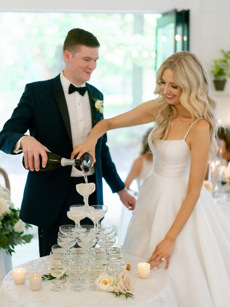Bride and groom pouring champagne into their champagne tower