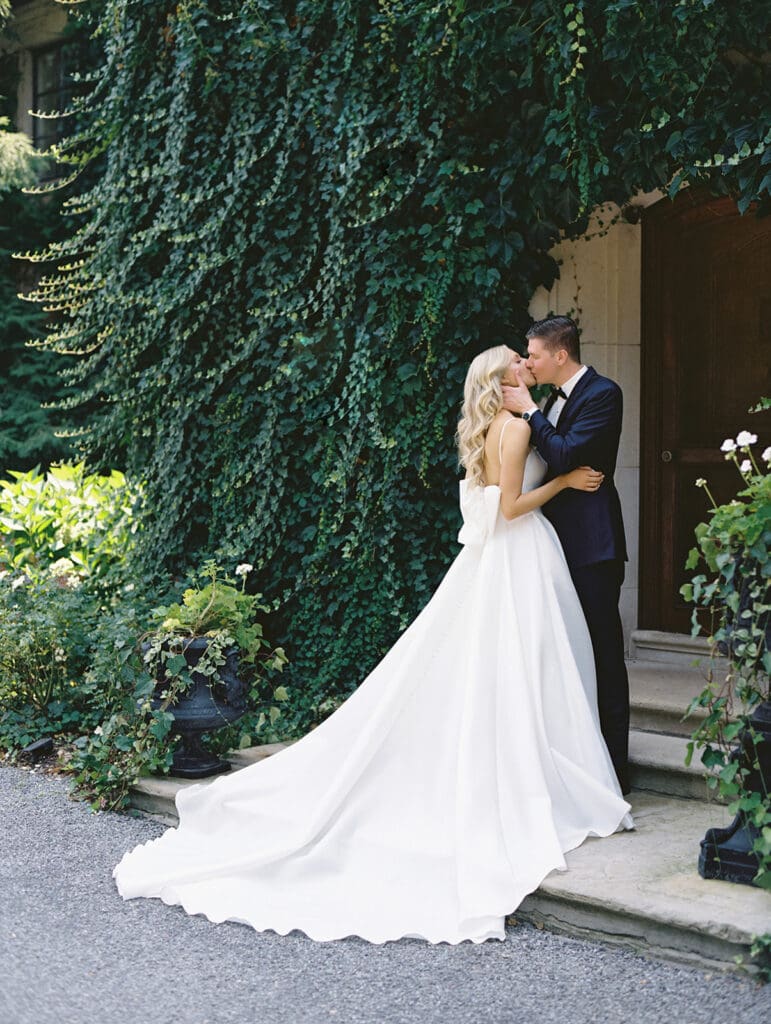 Bride and grooms kissing during their portraits outside of Greencrest Manor wedding venue in Battle Creek, Michigan