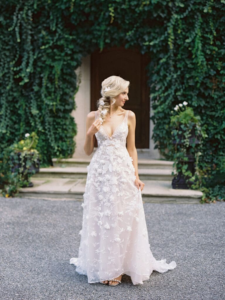 Bride wearing a long floral dress with a romantic loose braid adorned with flowers for her welcome wedding party at Greencrest Manor wedding venue. 