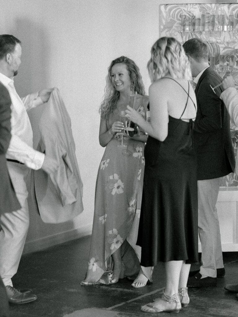 Black and white photo of wedding guests mingling during cocktail hour