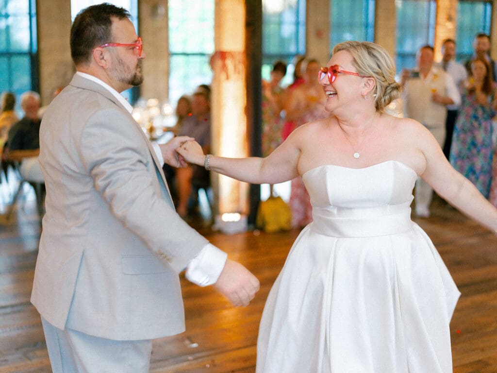 Bride and groom wearing heart sunglasses and sharing their first dance