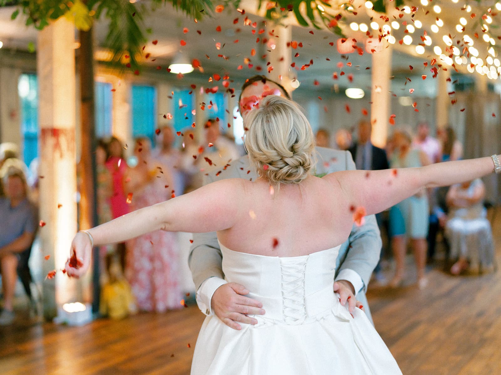 Bride and groom wearing heart sunglasses and sharing their first dance while confetti is dropping down on them