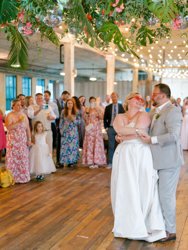 Bride and groom sharing their first dance with pink heart shaped glasses on
