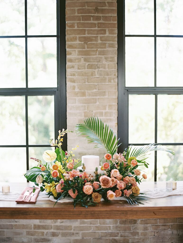 A white wedding cake with beautiful tropical florals all around