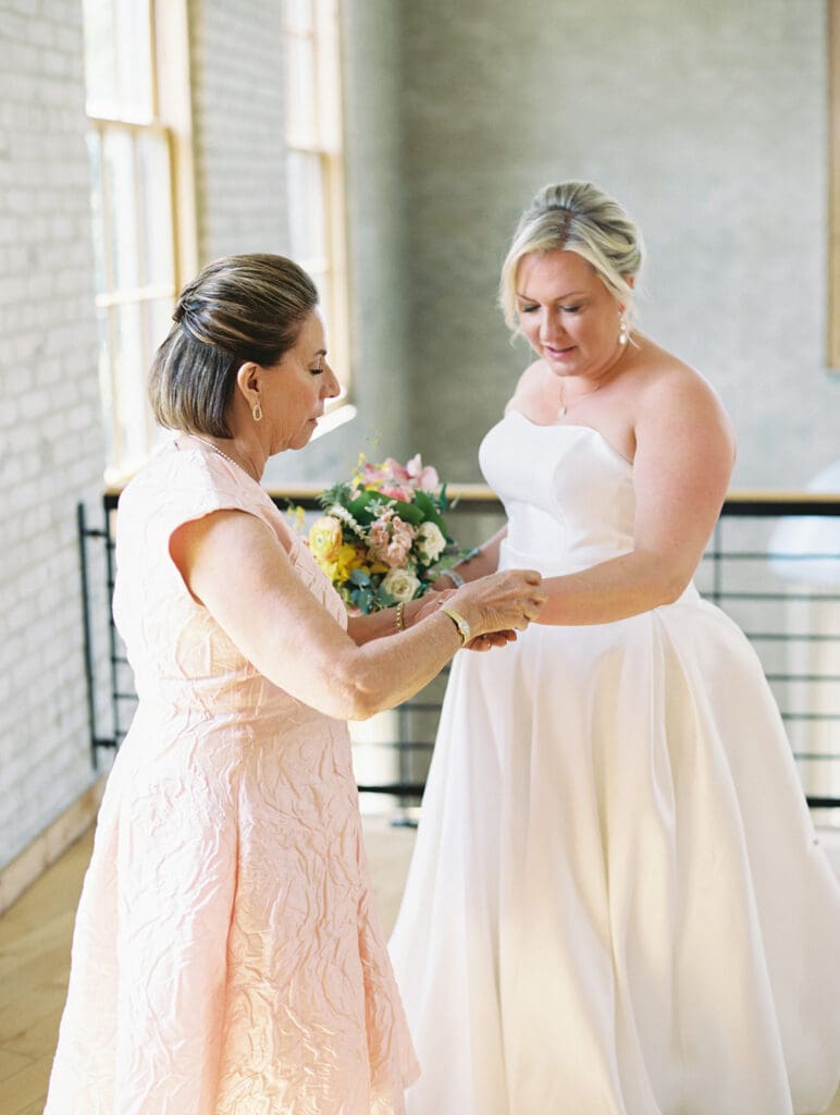 Brides mother putting her bracelet on for her 
